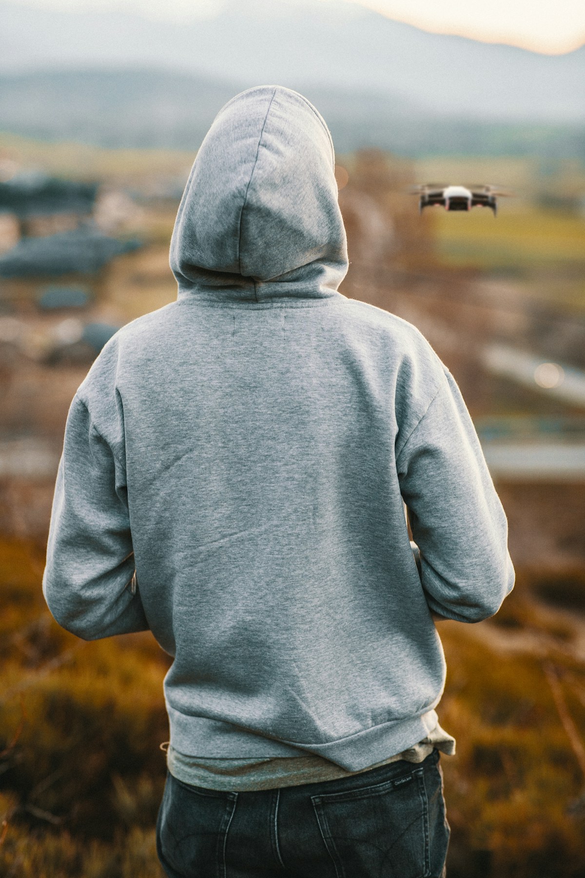 Grey hoodie showing its hood, sleeves and ribbed hem